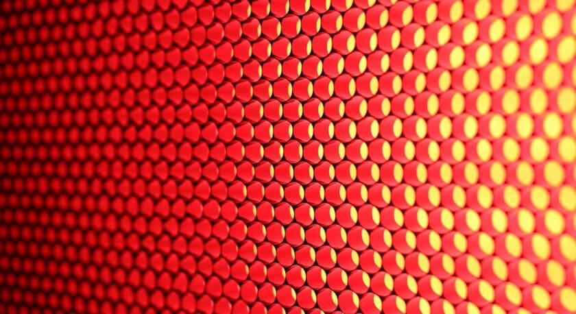 A close-up view of a textured surface featuring a pattern of hexagonal shapes. The predominant color is a vibrant red, with yellow accents highlighting the edges of the hexagons. The arrangement creates a visually striking and dynamic appearance, emphasizing the geometric design.